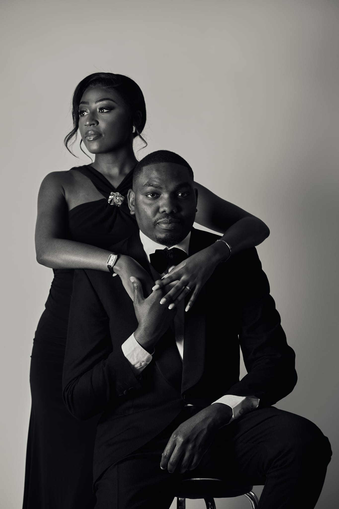 Portrait studio en noir et blanc : Annita se tient derrière Yann assis, les bras autour de lui.